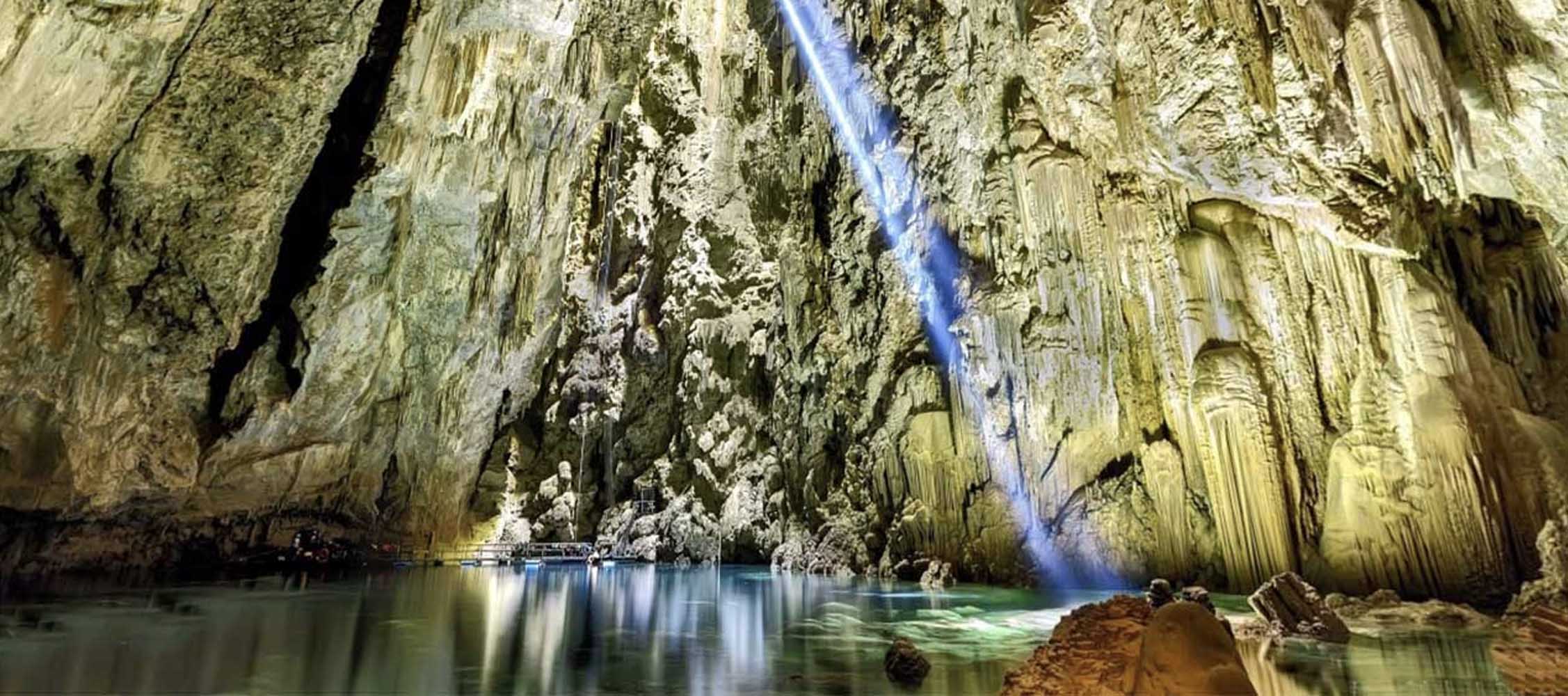 Vista do interior do Abismo Anhumas com lago cristalino e formações calcárias em Bonito.